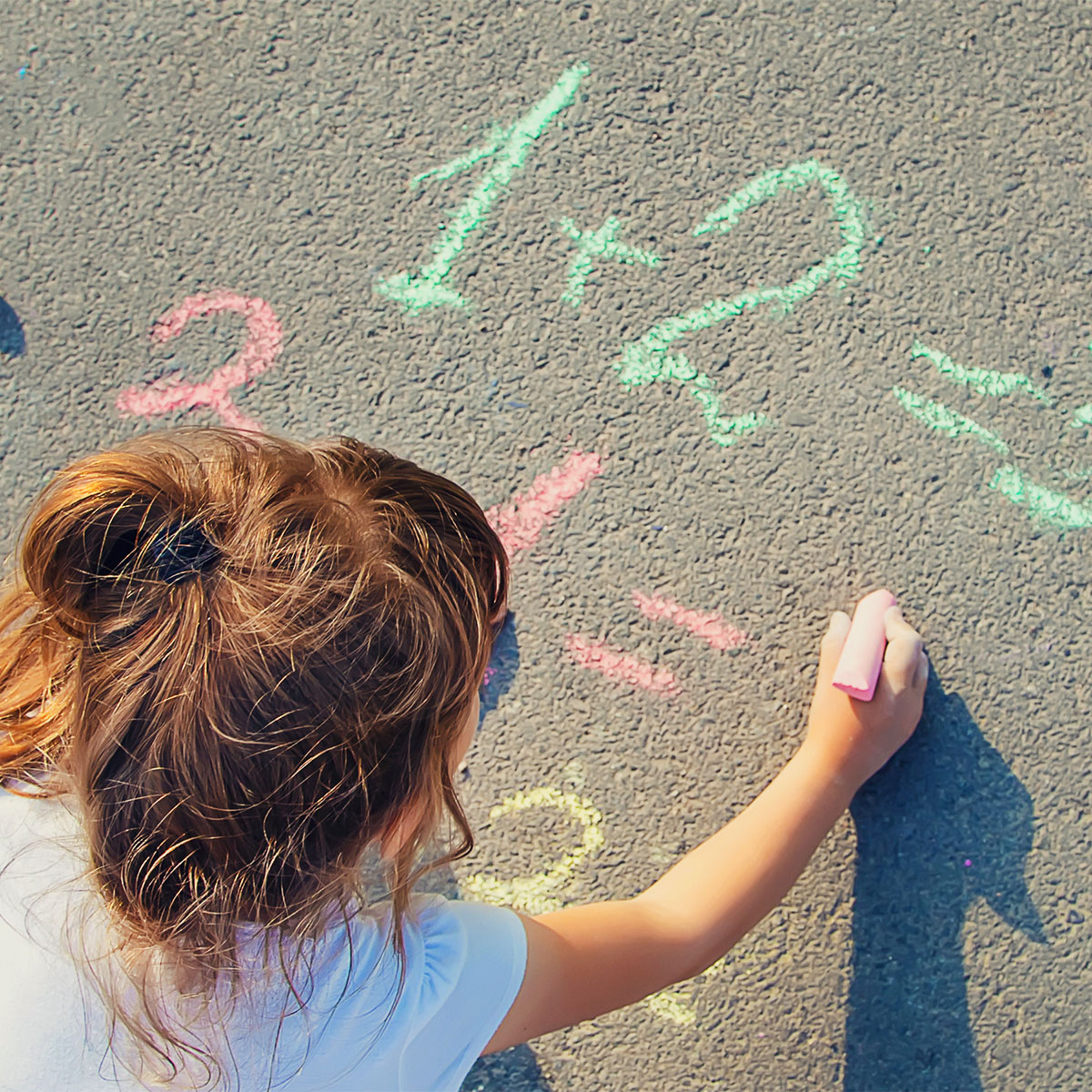 child doing math equations in chalk on sidewalk